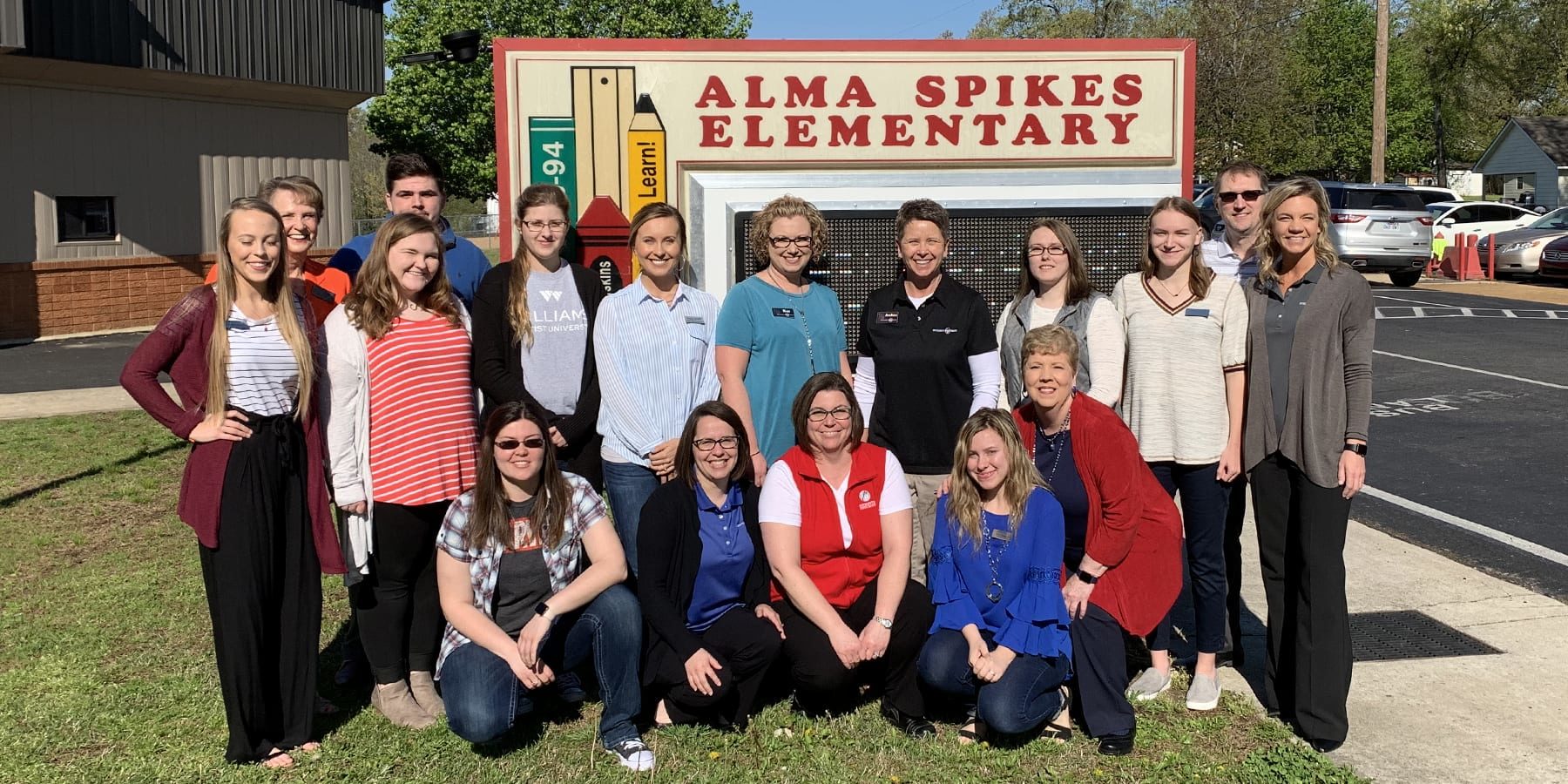 A group of people pose in front of Alma Spikes Elementary School.